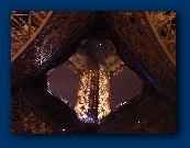 Looking up the middle of the Eiffel Tower from underneath it.